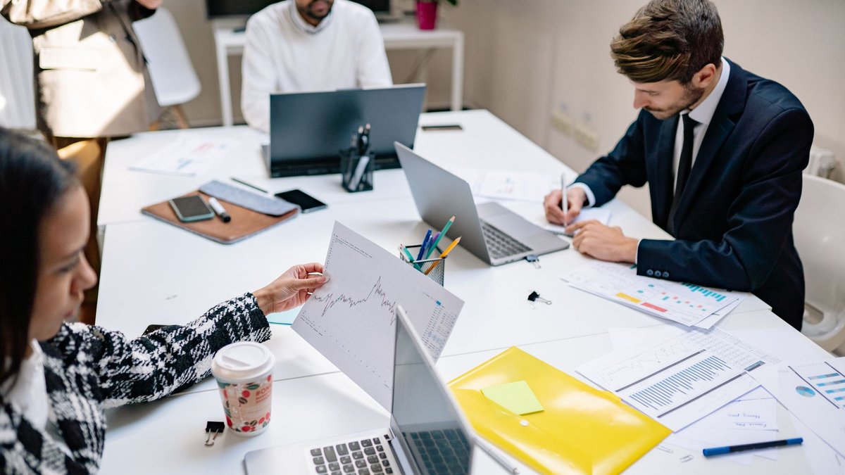 Equipe de marketing reunida analisando relatórios e gráficos em um escritório