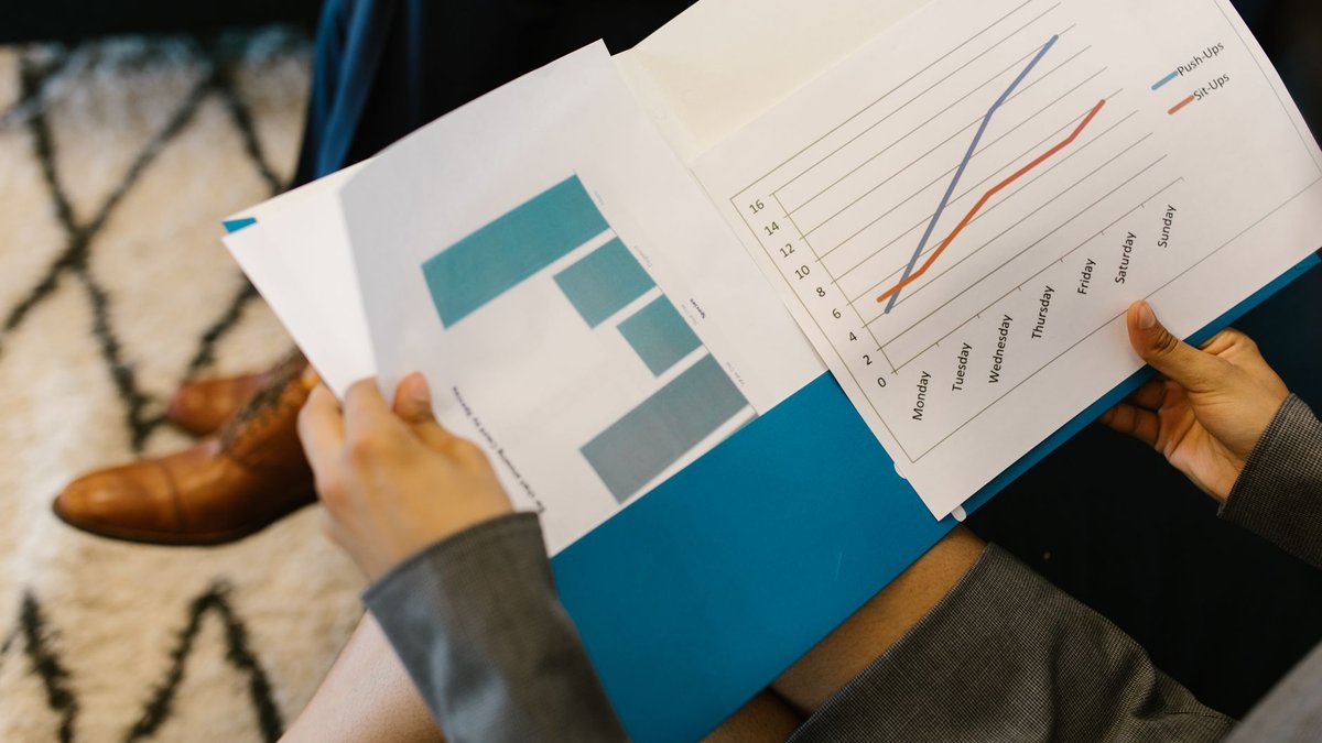 Mãos segurando relatórios impressos com gráficos de desempenho